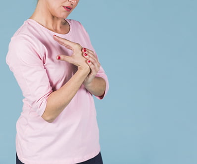 woman holding her painful wrist against blue background
